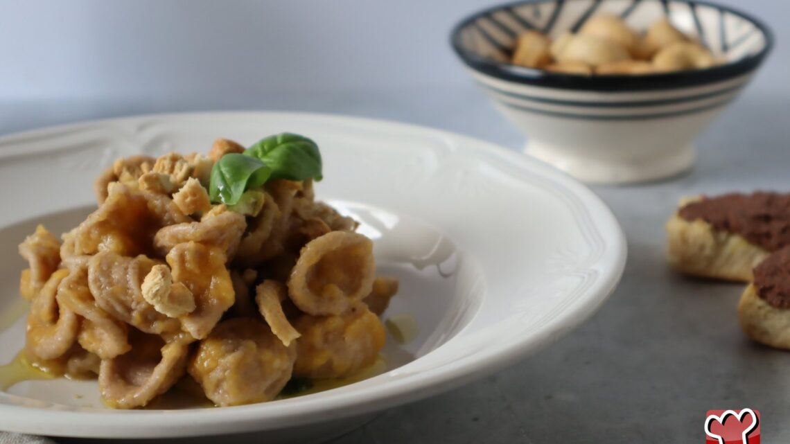 Orecchiette al grano arso con passata di pomodoro giallo, briciole di taralli e basilico, in un piatto fondo bianco