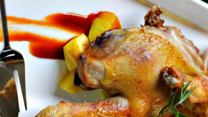 Galletto arrosto intero con patate, in un piatto bianco